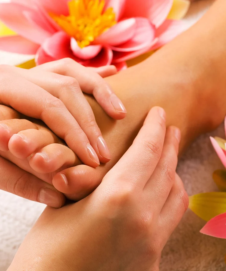 A close-up of a foot massage with flowers and fresh towels