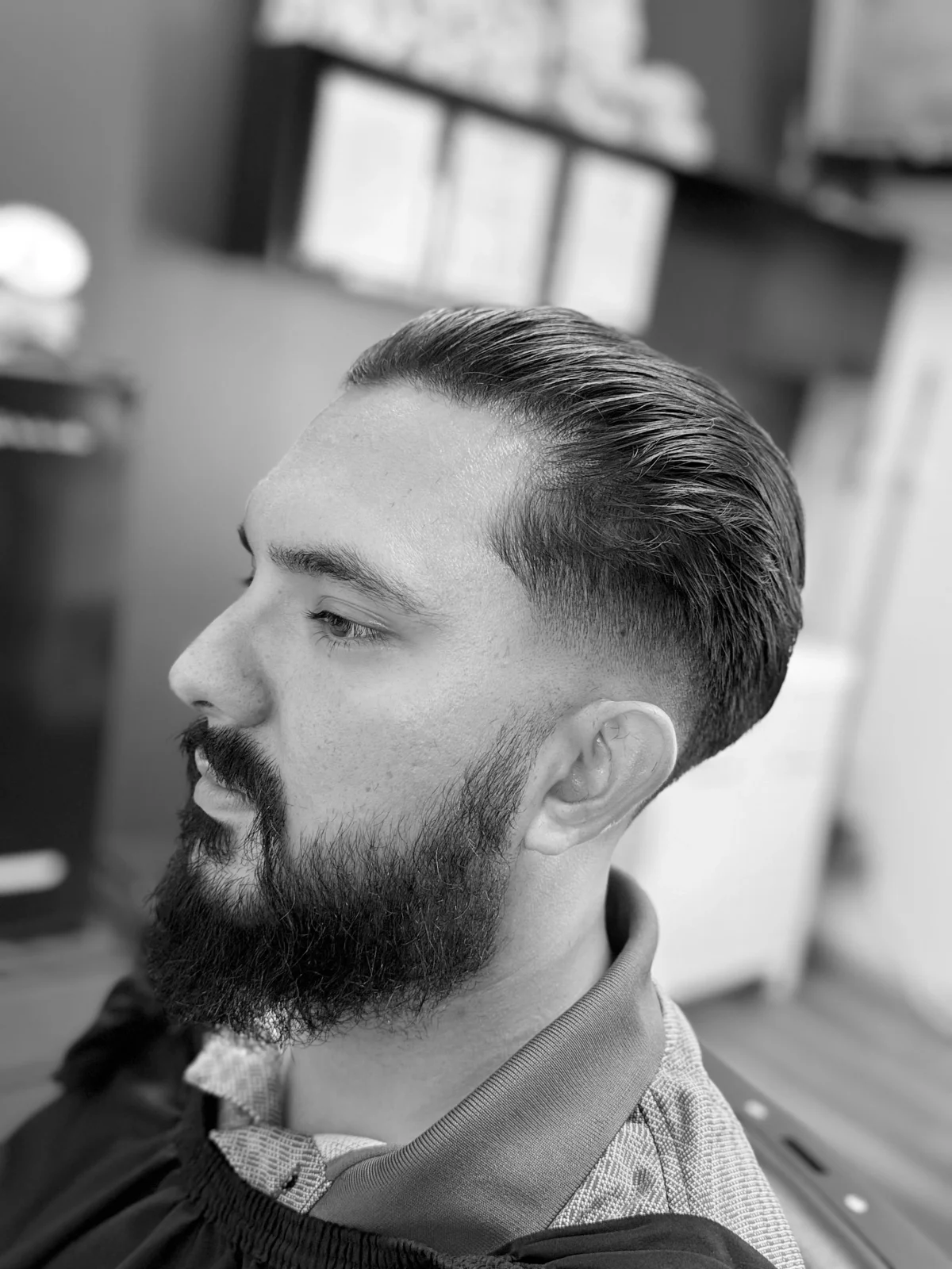 Combed-back haircut with a defined dark beard at PLATA