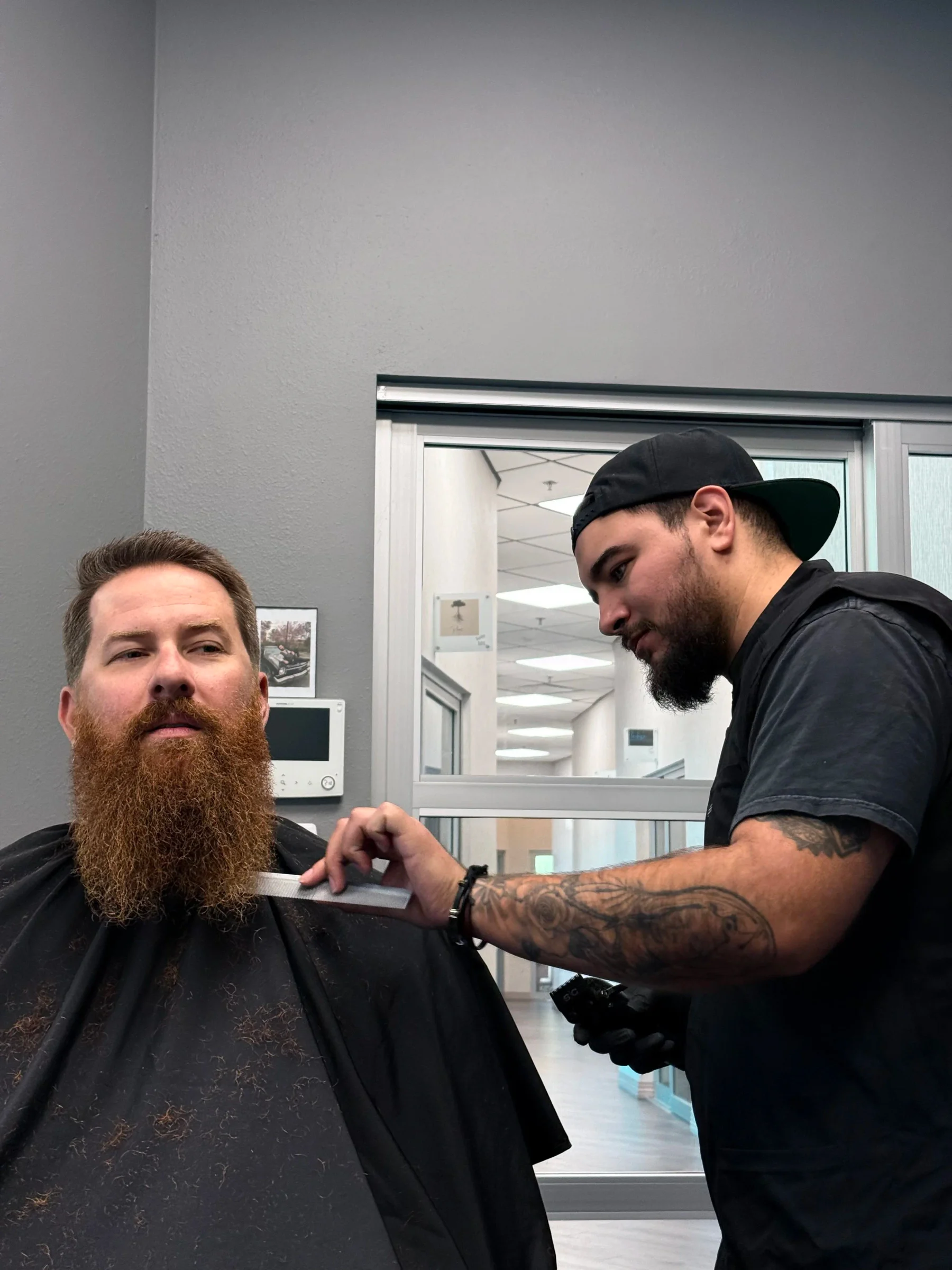 A PLATA barber carefully trimming a client’s full beard in the Woodstock shop